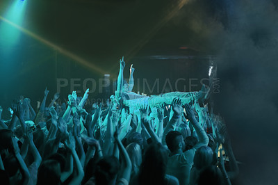 Buy stock photo Crowd surf, blue light and people at concert or at music festival, lights and energy at live event. Dance, fun and group of excited fans in arena at rock show performance, group carrying fan on hands