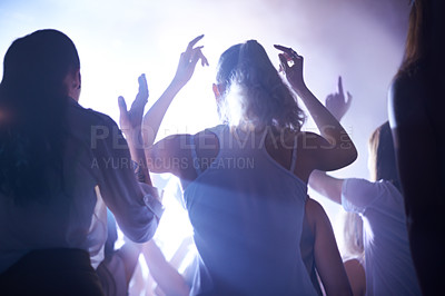 Buy stock photo Concert, music festival and women from back, lighting and energy in crowd at live night event. Dance, fun and group of excited fans in arena at rock band performance or audience at techno rave party.