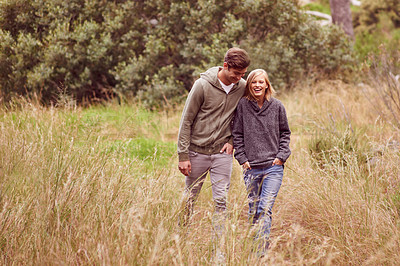 Buy stock photo A young couple laughing as the walk in a field
