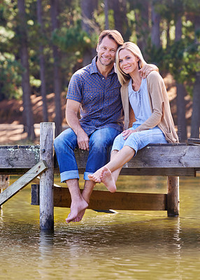 Buy stock photo Mature couple, portrait and lake of countryside and together for love in marriage. Happiness, smile and hug by partner, family and woman with man sitting on dock for sightseeing and relax in nature 
