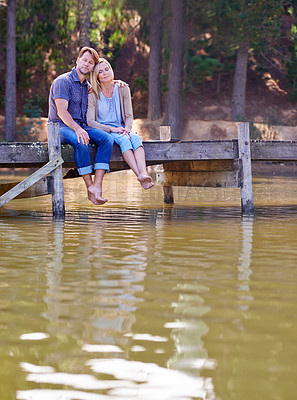 Buy stock photo Mature couple, together and relax in lake, countryside and commitment with love in marriage. Happiness, smile and hug by partner, family and woman with man sitting on dock for sightseeing in nature