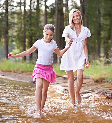 Buy stock photo A cute little girl running through a wilderness stream with her mother