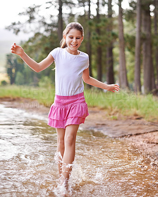 Buy stock photo Little girl, smile and countryside in stream with happiness, feet and game of walking. Child, cute and playing in nature with joy, carefree and freedom on warm summer, water splash and energy