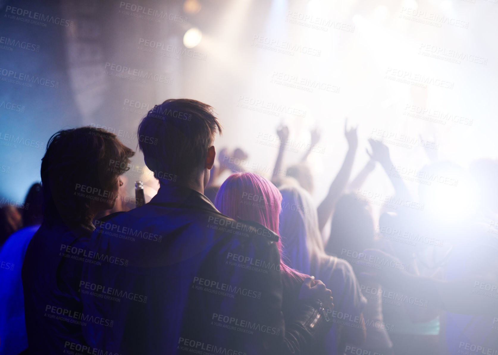 Buy stock photo Dance, rock and friends in crowd at music festival from back, watching live band performance on stage. Audience in arena, lights and group of people at party, fans of musician at concert together.