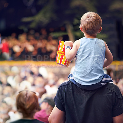 Buy stock photo Rearview shot of a young boy sitting on his father's shoulders at an outdoor festival