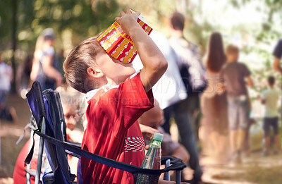 Buy stock photo Festival, party and boy eating popcorn outdoor in summer at event for celebration or entertainment. Kids, food or snack and young child eating from box in nature, forest or woods alone with chair
