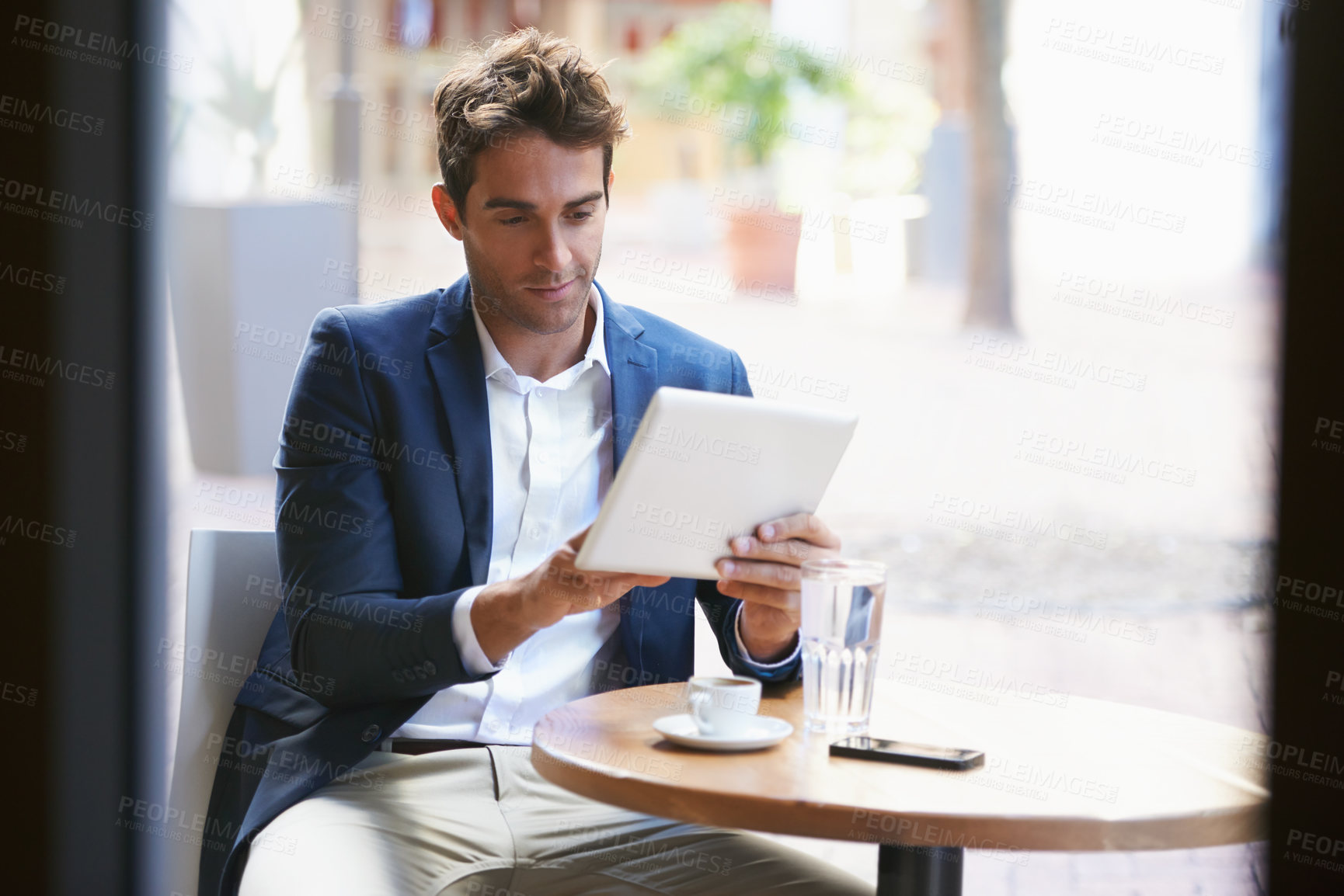 Buy stock photo Shot of a young businessman enjoying a cup of coffee while using a digital tablet