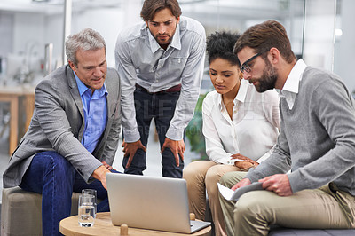 Buy stock photo Shot of a diverse group of office professionals talking around a laptop
