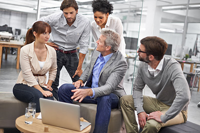 Buy stock photo Shot of a diverse group of office professionals talking around a laptop