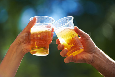 Buy stock photo Cropped view of two people saying cheers with their beer cups