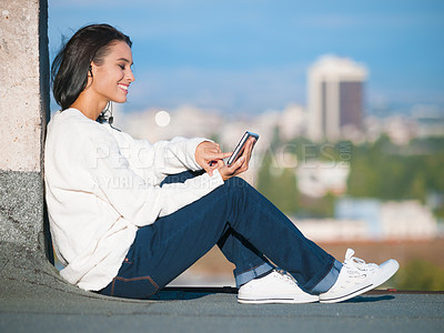 Buy stock photo Shot of an attractive young woman listening to music on her tablet on a rooftop