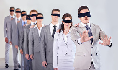 Buy stock photo A row of blindfolded businesspeople following a blindfolded leader