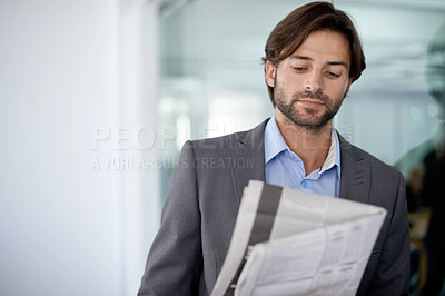 Buy stock photo A young businessman reading a newspaper in the office