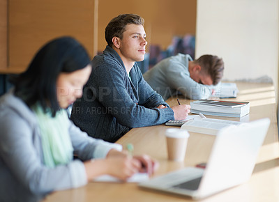 Buy stock photo A young man studying the library with other students