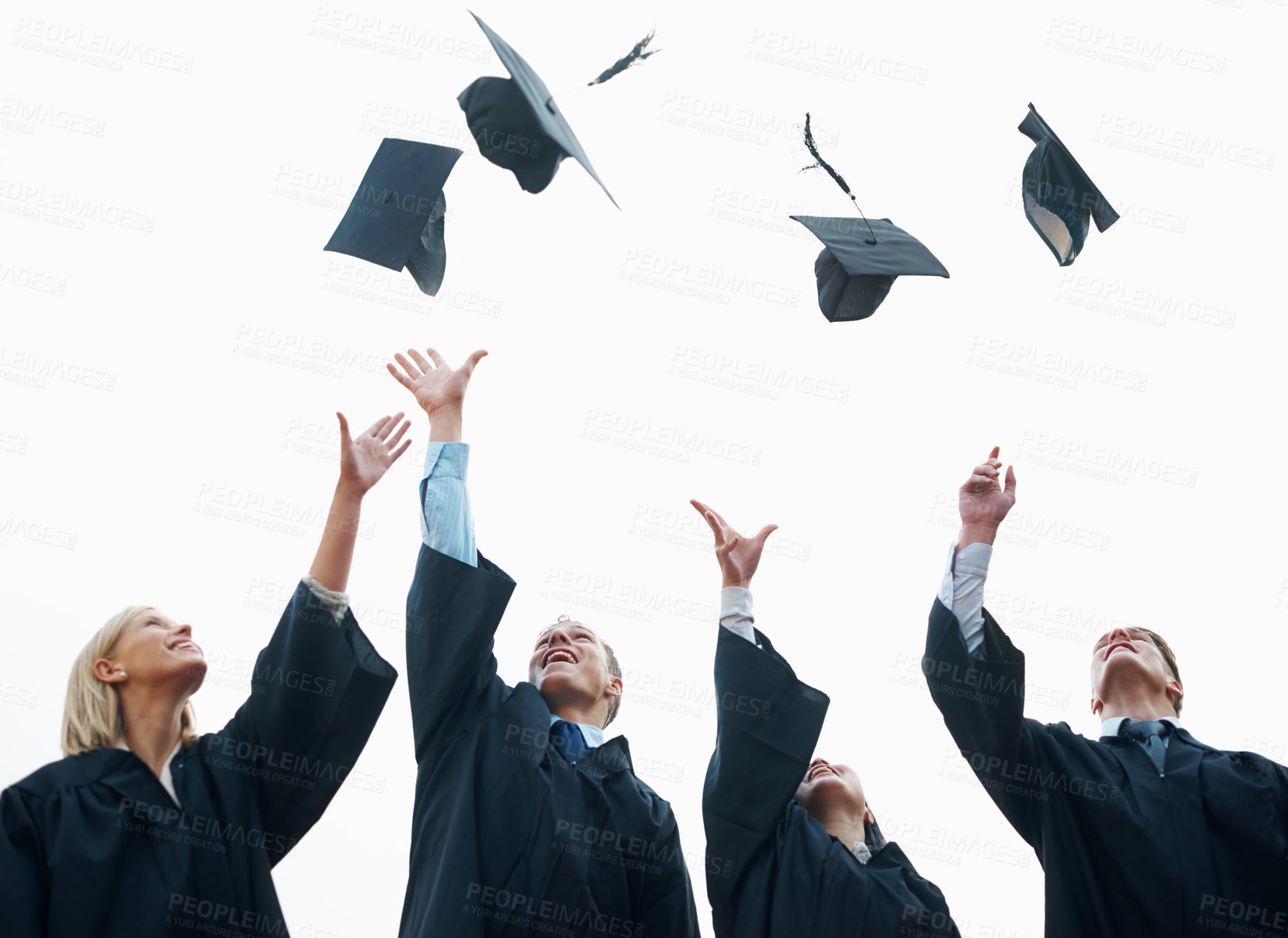 Buy stock photo A group of students throwing their caps into the air after graduation