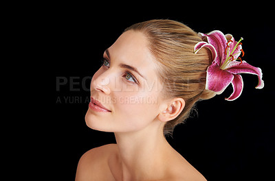 Buy stock photo An attractive young woman with a flower in her hair against a black background
