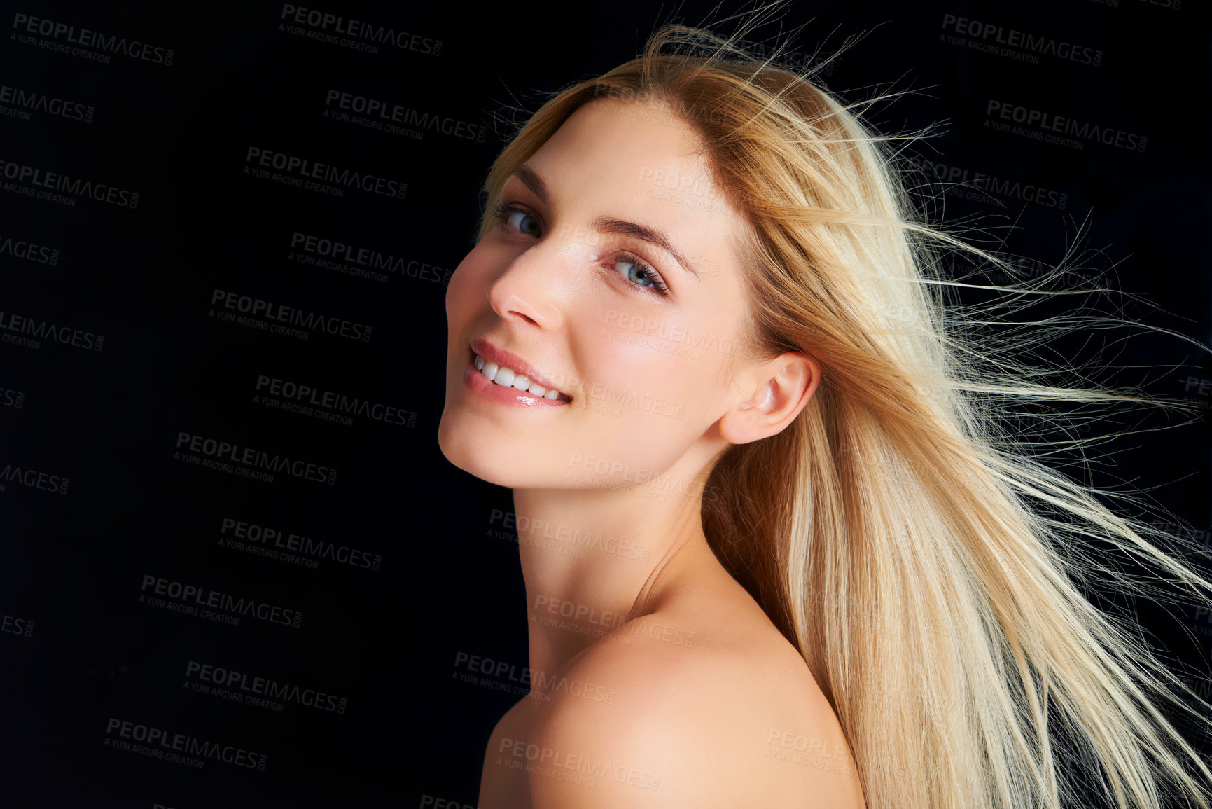 Buy stock photo A blonde woman posing in front of a black background while the wind blows through her hair
