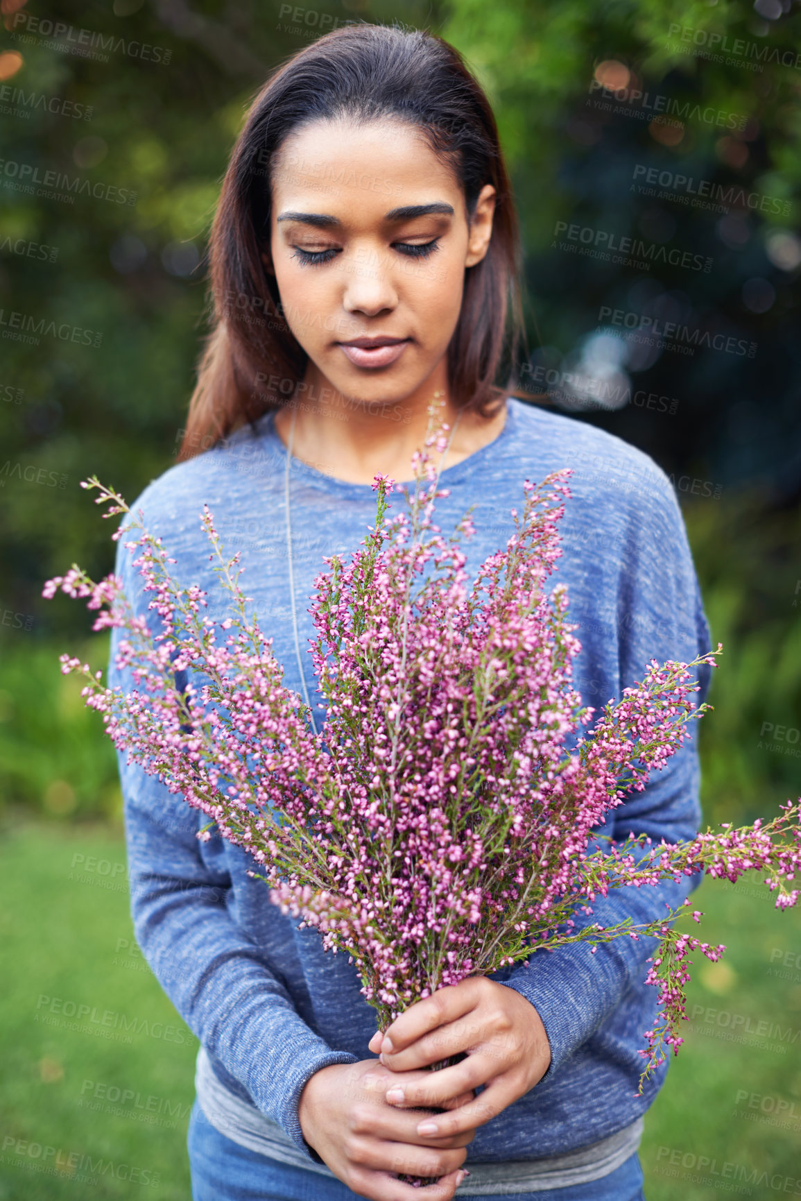 Buy stock photo A young woman holding a bunch of flowers in a garden