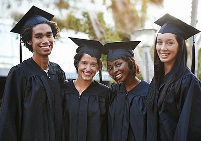 Buy stock photo A group of smiling college graduates standing together in cap and gown