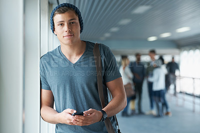 Buy stock photo Shot of a handsome young college student holding a cellphone with friends in the background