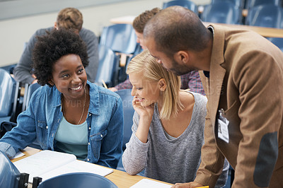 Buy stock photo A young man speaking to two girls sitting in a lecture room