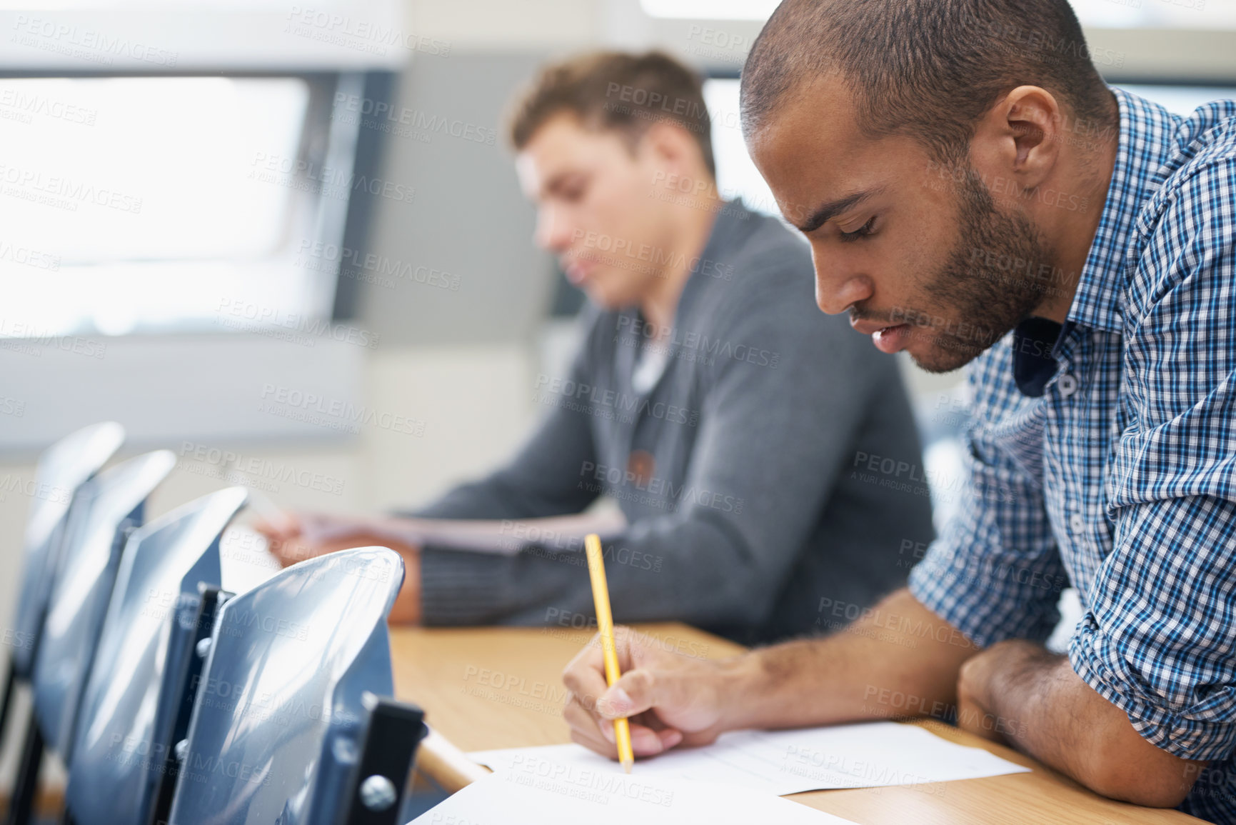 Buy stock photo Two male students writing exam in a lecture hall