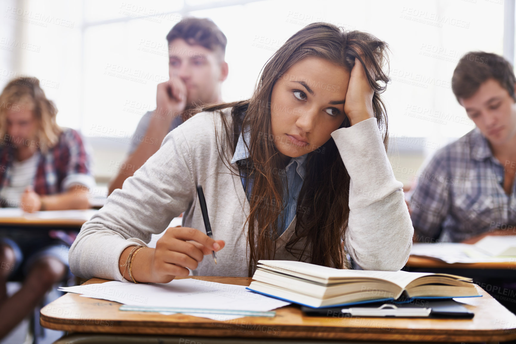 Buy stock photo An overworked young student sitting with her head in her hands