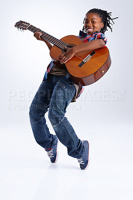 Buy stock photo A happy young African-American boy playing a guitar while balancing on his toes