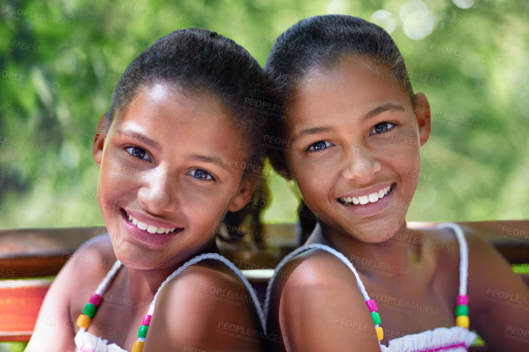 Buy stock photo Cropped portrait of two twin sisters sitting on a park bench