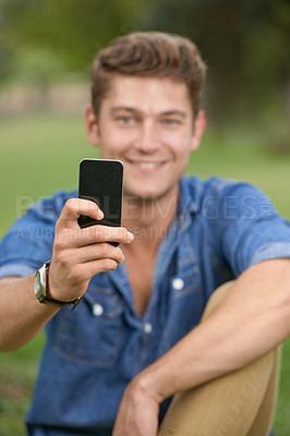 Buy stock photo Portrait of a young man taking a picture with his cellphone