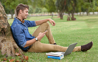Buy stock photo Shot of a handsome young man studying in the park with a laptop