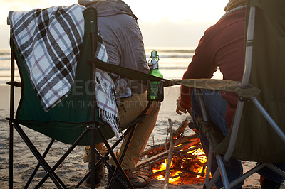 Buy stock photo Beer, beach and man friends by fire on sand by ocean or sea together for travel, holiday or vacation. Nature, relax and people drinking on coast from back with view of sunset, horizon and coast