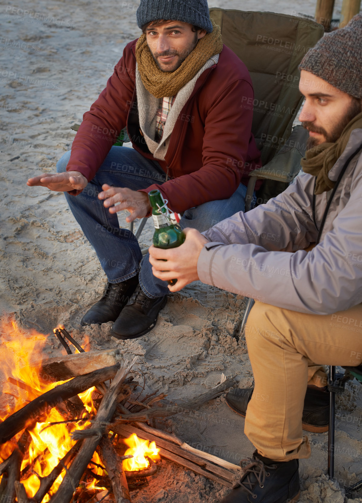 Buy stock photo Men, sunset and campfire with portrait, smile and beer with travel adventure and journey outdoor. Friends, ocean and sea with bonding, winter and vacation by the beach together on holiday with fire