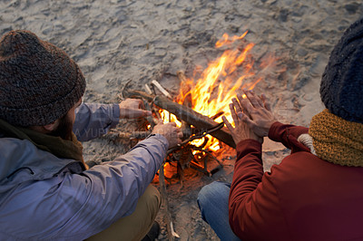 Buy stock photo Hands, campfire and friends at beach on holiday, vacation and travel to warm up in winter outdoor. Flame, wood and people together by sand at seashore for leisure, adventure and top view in nature