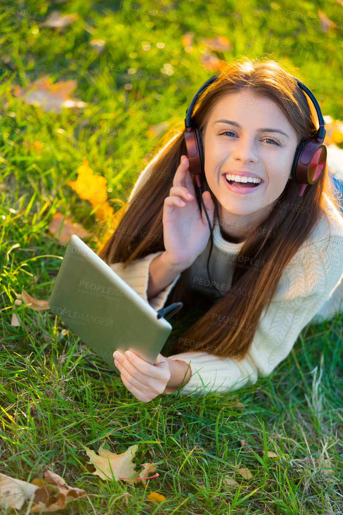 Buy stock photo An attractive young woman listening to music on her digital tablet while outdoors