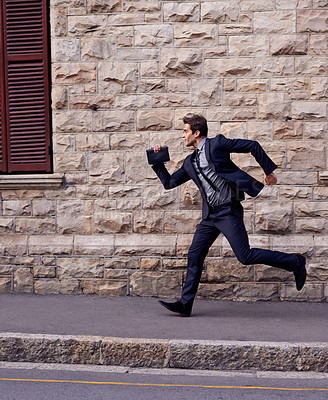 Buy stock photo Shot of a young businessman running down a street