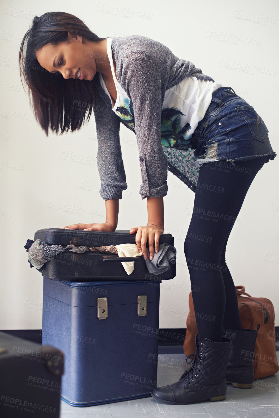 Buy stock photo A woman trying to close an over-full suitcase