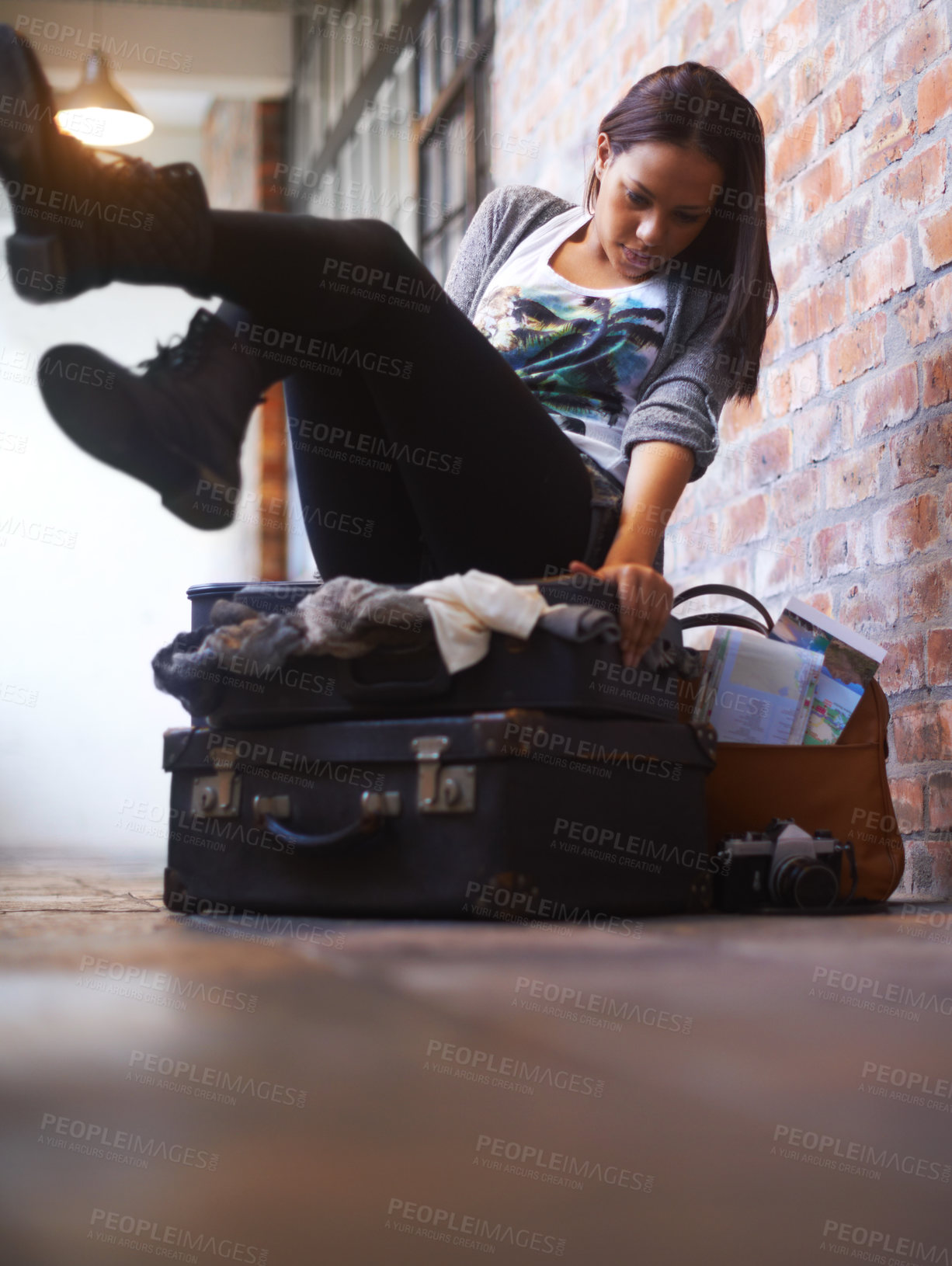 Buy stock photo A young woman trying in vain to close an over-full suitcase