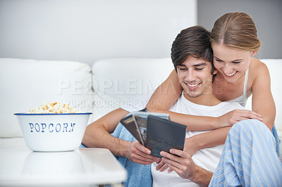 Buy stock photo Couple, popcorn and choice for movie, living room and date for comfortable home bonding. People, relationship and love with film, relaxation and smile for happiness or break with snack for eating
