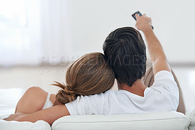 Buy stock photo Rear view shot of a young couple watching TV together