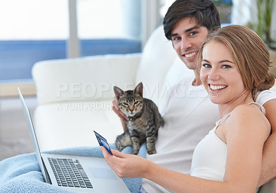 Buy stock photo Shot of a young couple with a kitten shopping online