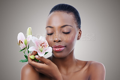 Buy stock photo Eyes closed, flowers and black woman with shine, grooming and treatment on grey studio background. African person, girl and model with organic cosmetics and beauty with skincare, glow and aesthetic