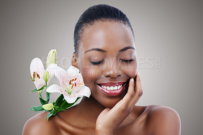 Buy stock photo Eyes closed, flower and black woman with skincare, smile and natural cosmetics on grey studio background. African person, girl or model with plants or beauty with shine, aesthetic or glow with luxury