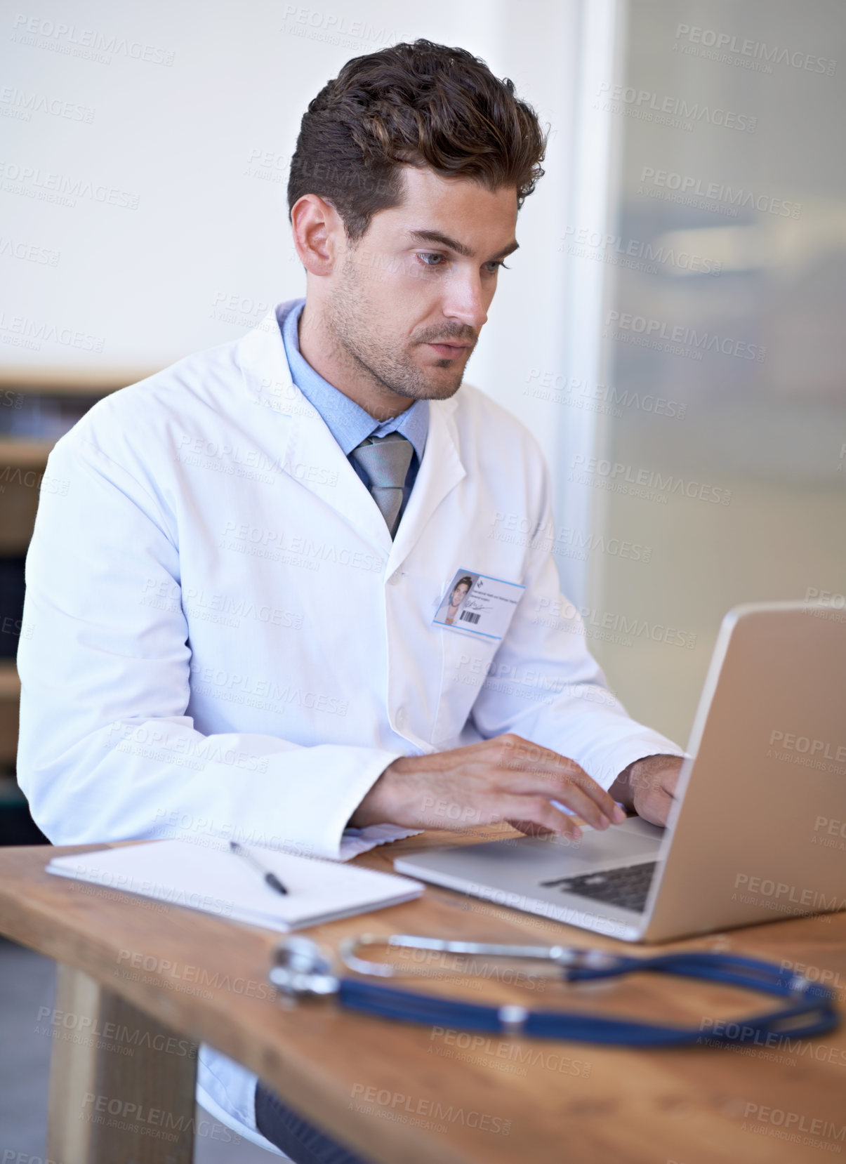 Buy stock photo Shot of a young doctor at work on a laptop