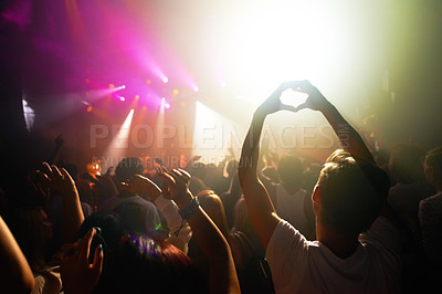 Buy stock photo Crowd at concert, music and watch band performance, music festival, light and energy with audience back view. People dance with hands in heart shape, musician on stage and festival in Florida.
