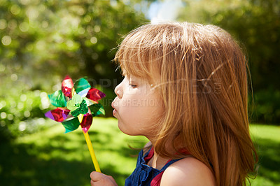 Buy stock photo Young girl, outdoor and blowing pinwheel, garden and enjoying freedom of outside and happy. Pretty little child, backyard and summer for playing, toy and windmill for school holidays and happiness
