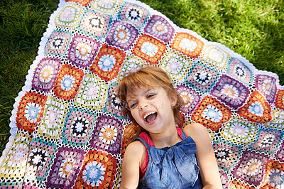 Buy stock photo Laughing, top view and kid on blanket outdoor on grass in nature, smile and relax in summer. Funny, above and face of girl child on lawn with excited facial expression for comedy, joke and humor