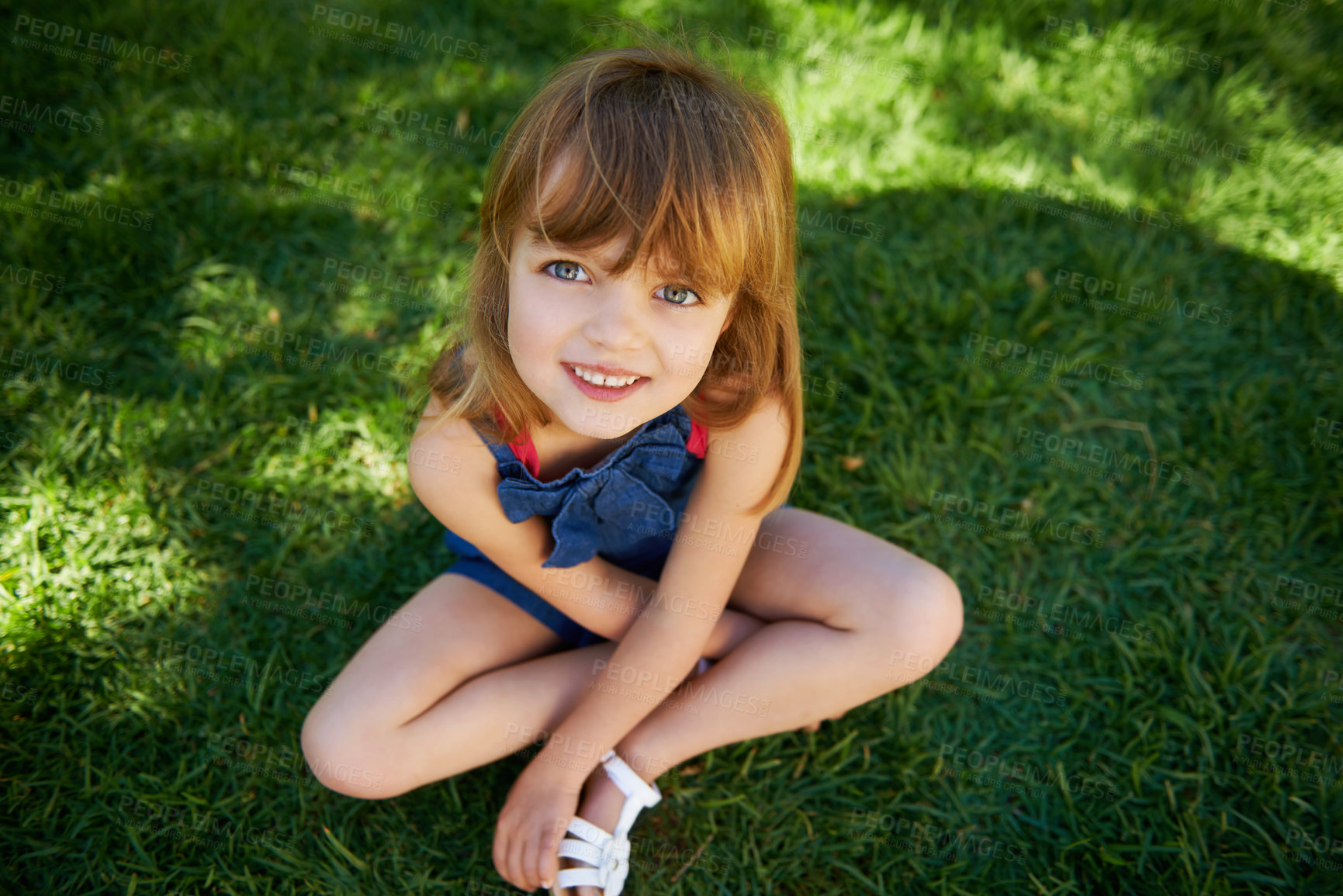 Buy stock photo Shot of a cute little girl smiling while lying down on grass