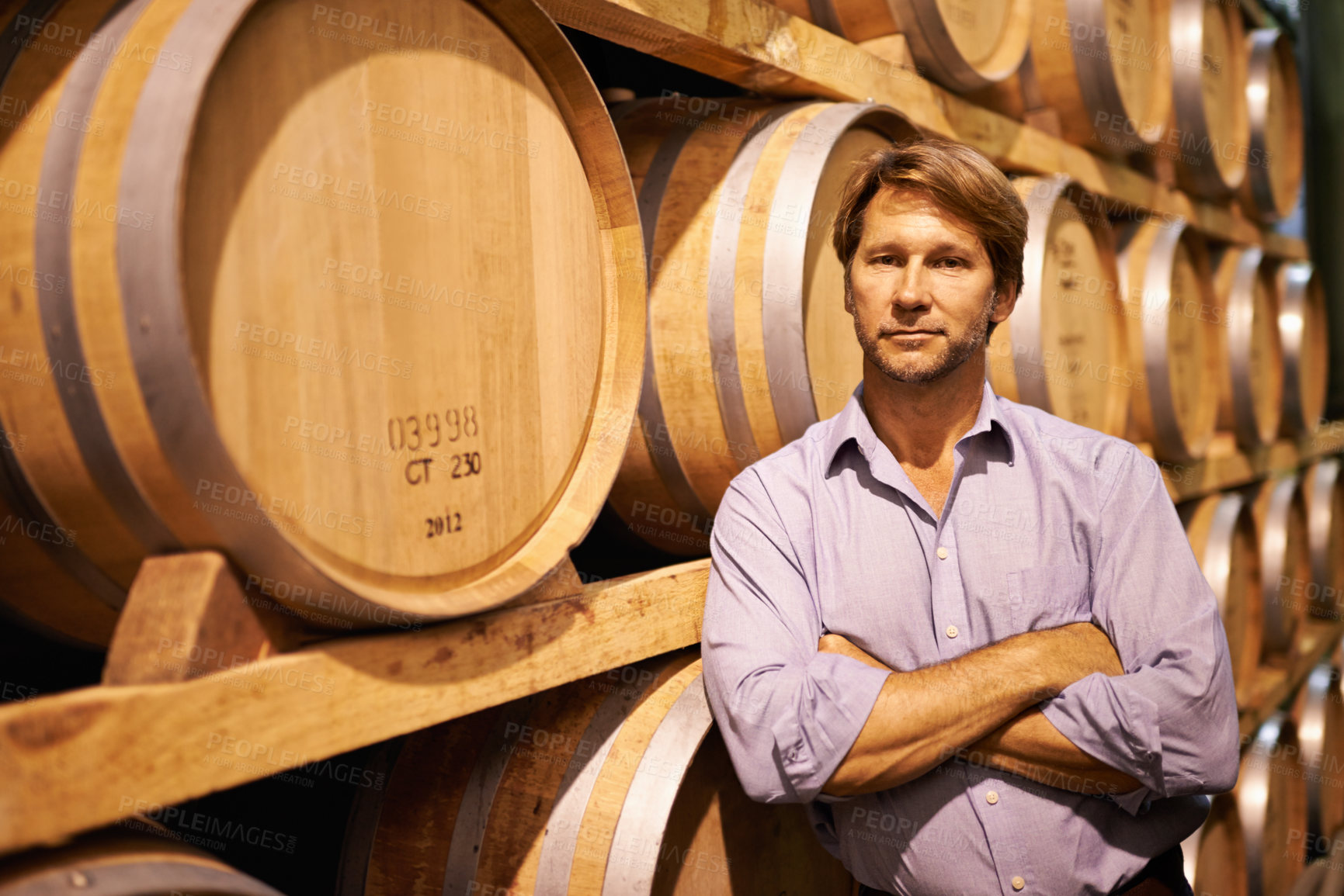 Buy stock photo Shot of a handsome mature man standing in a wine cellar