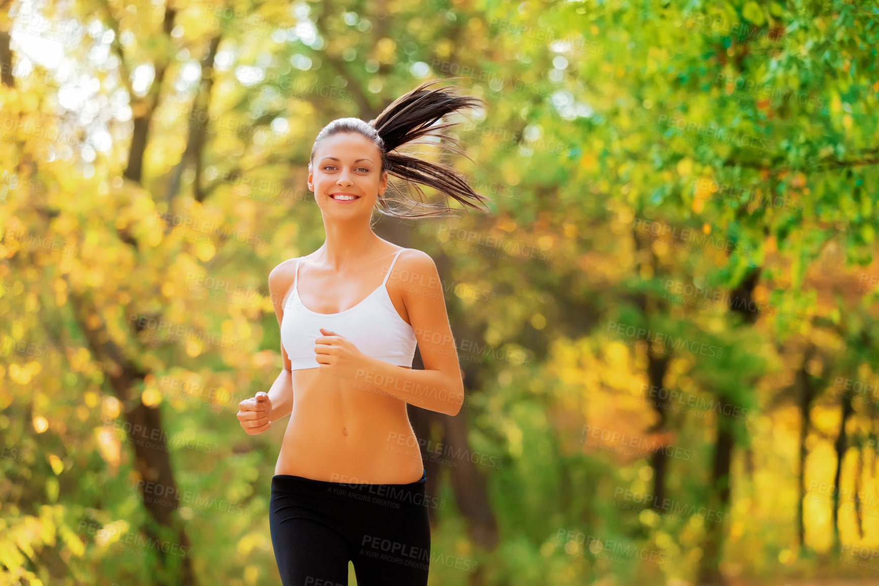 Buy stock photo Shot of a positive-looking young woman jogging in a park in autumn